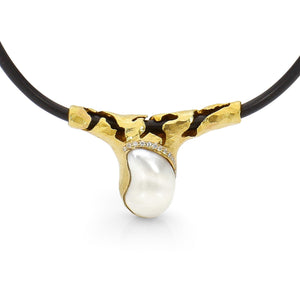 Keshi pearl pendant on black neoprene. Keshi is set in heavy yellow gold that is wrapped around the neoprene with cut outs to that you can see the neoprene through the gold. There are channel set white diamonds above the Keshi pearl.